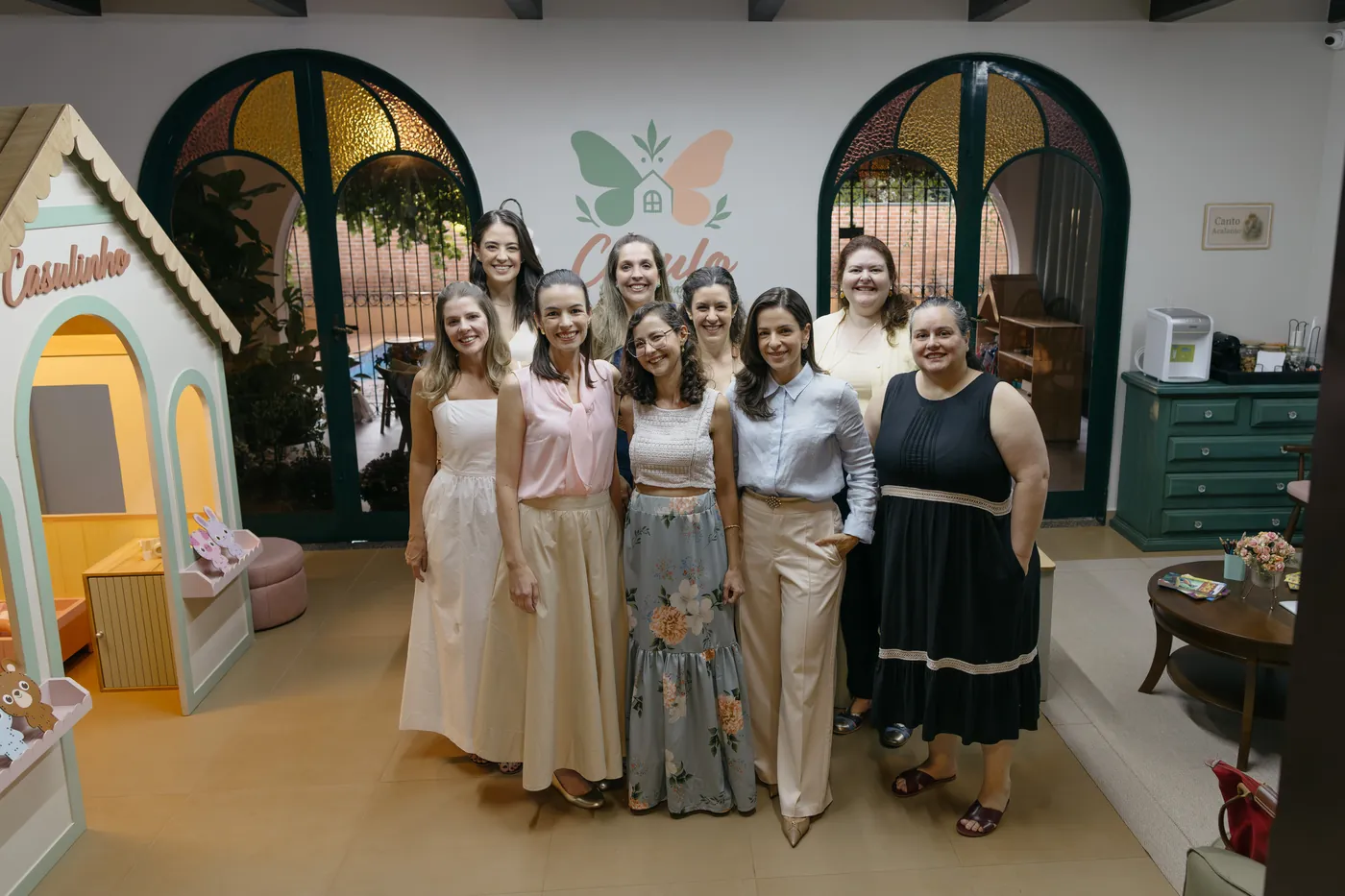 Equipe do Espaço Casulo reunida na recepção, com a área infantil Casulinho ao fundo