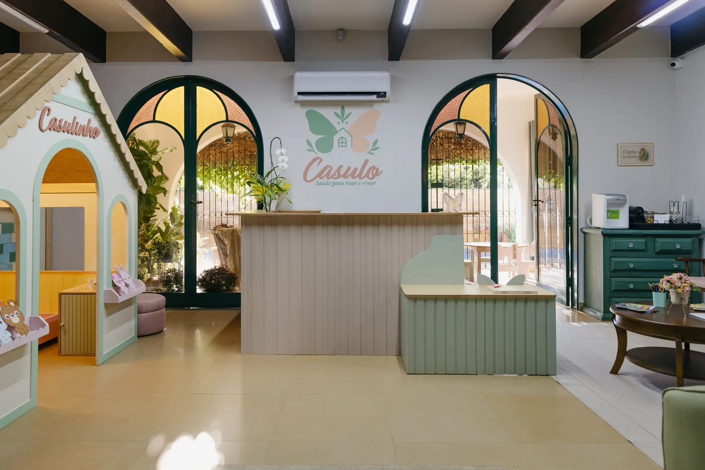 Recepção do Espaço Casulo com portas em arco e balcão em verde sálvia